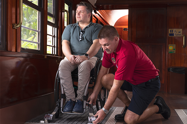 A team member seciring a customer's tie-down straps to their mobility device.